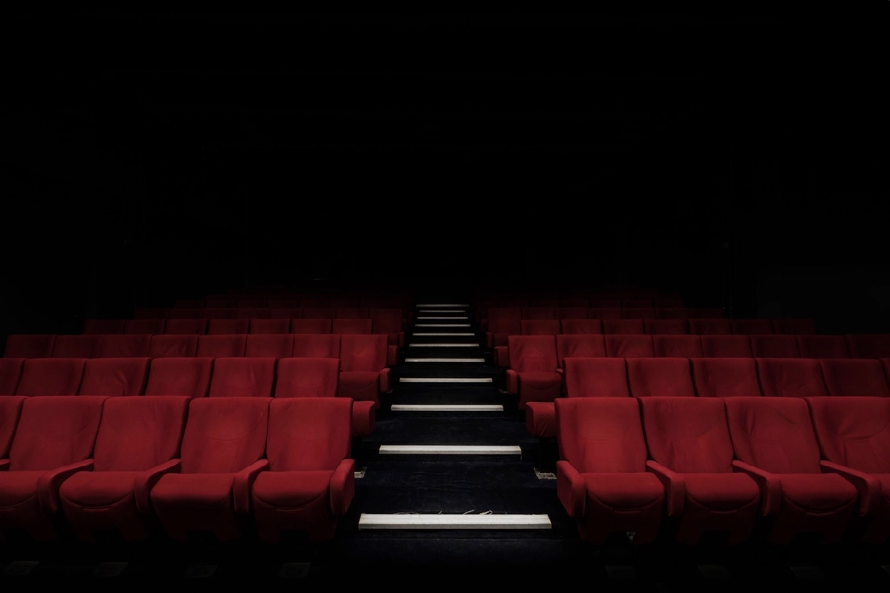 Empty cinema with rows of red seats in the dark